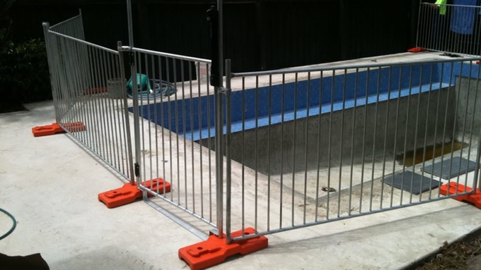 A temporary pool fence gate is installed with temporary fence around a no water swimming pool.
