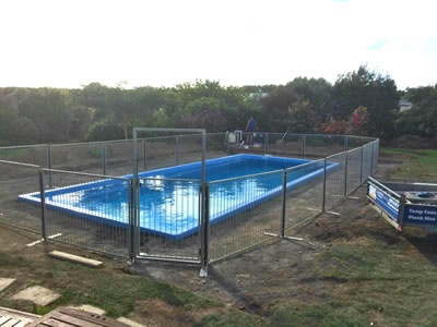 Temporary pool fencing and gate installed around a outdoor swimming pool.