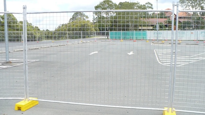 A galvanized Australia temporary fence installed with the yellow plastic moulded feet standing on the concrete.