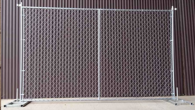 A chain link temporary fence panel is standing next to the hoarding. The panel has a vertical reinforced pipe.
